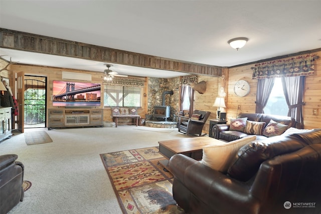 living area with a wood stove, wood walls, carpet, and a wealth of natural light