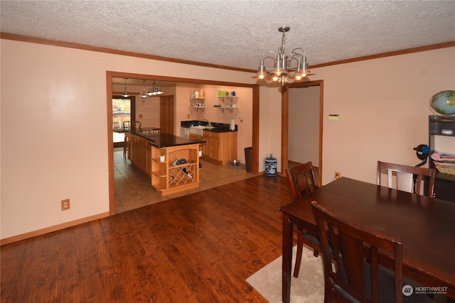 dining room featuring a textured ceiling, a chandelier, hardwood / wood-style floors, and sink