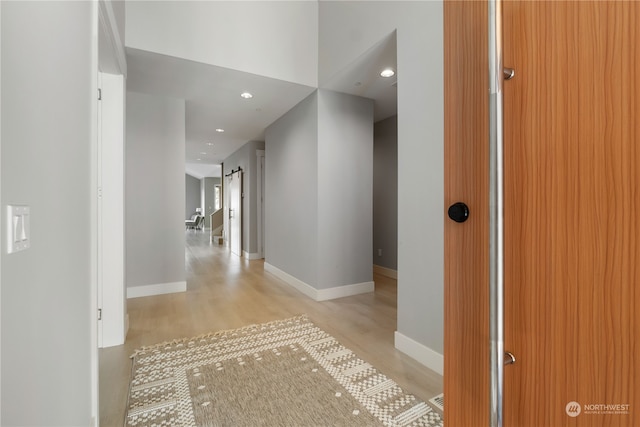 corridor with a barn door and light hardwood / wood-style flooring