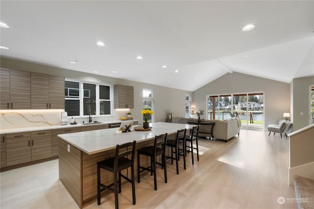 kitchen featuring a kitchen island, lofted ceiling, sink, a breakfast bar area, and light hardwood / wood-style flooring