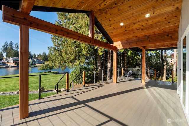 wooden terrace with a water view and a lawn