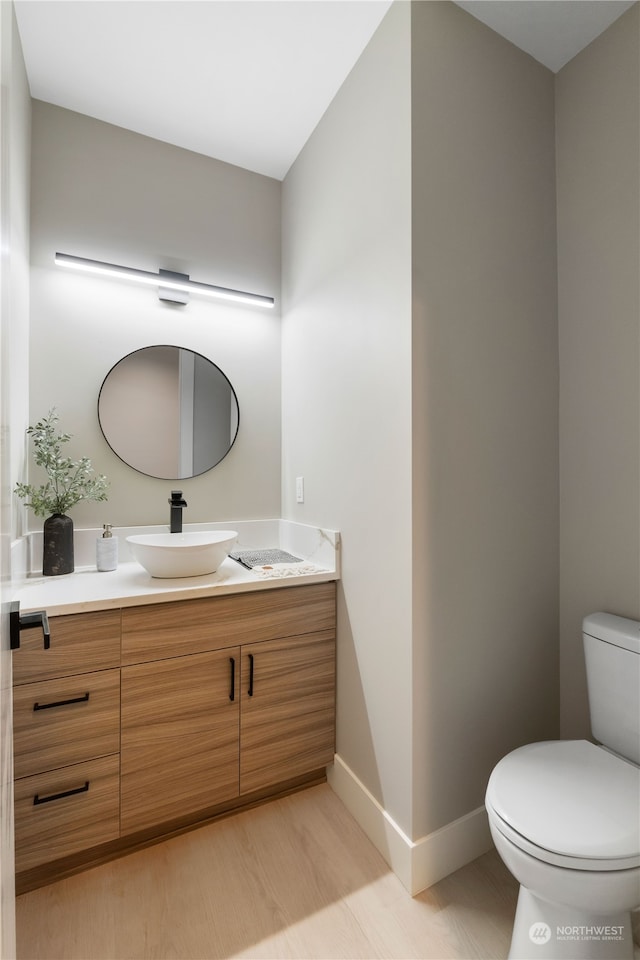 bathroom with vanity, toilet, and hardwood / wood-style flooring