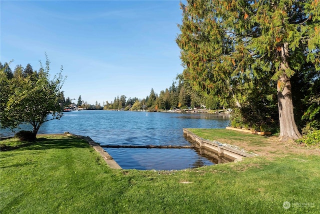 view of dock with a water view and a yard