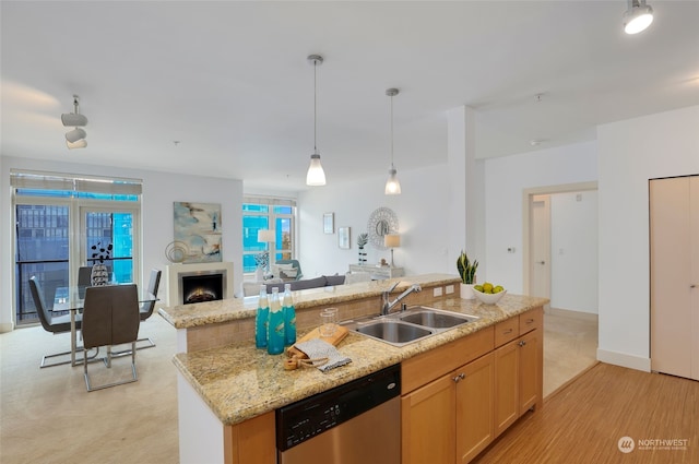 kitchen with stainless steel dishwasher, sink, light colored carpet, and a center island with sink