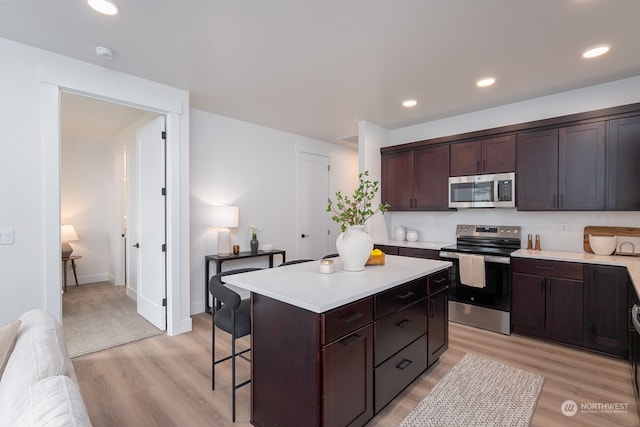 kitchen featuring dark brown cabinetry, light hardwood / wood-style flooring, a kitchen island, and stainless steel appliances