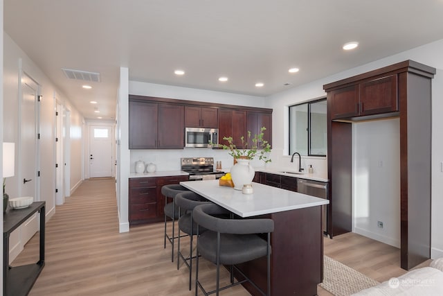 kitchen featuring a breakfast bar, a center island, stainless steel appliances, and light hardwood / wood-style floors