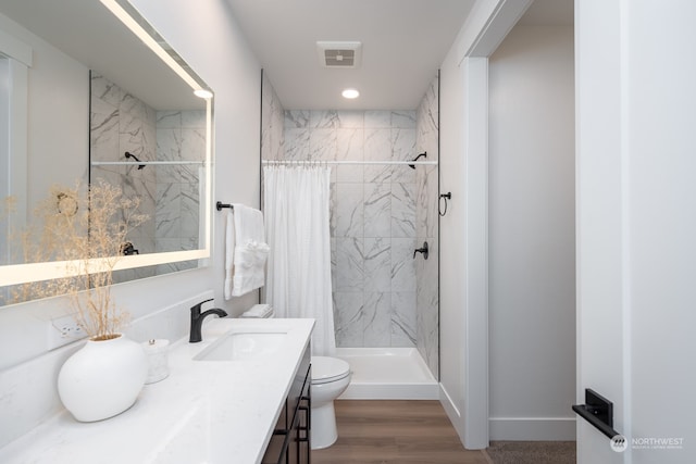 bathroom featuring hardwood / wood-style floors, a shower with curtain, toilet, and vanity