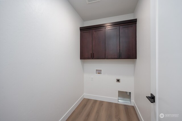 clothes washing area with cabinets, hookup for a washing machine, light wood-type flooring, and electric dryer hookup