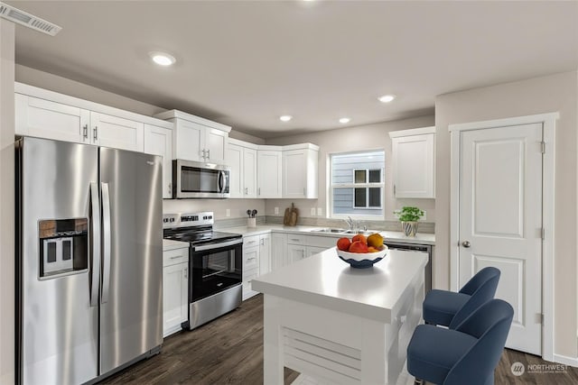 kitchen featuring white cabinetry, stainless steel appliances, a center island, and sink