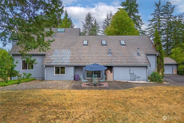 exterior space featuring a garage, a patio area, and a lawn