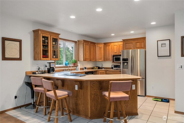 kitchen featuring appliances with stainless steel finishes, a breakfast bar area, kitchen peninsula, and light tile patterned flooring