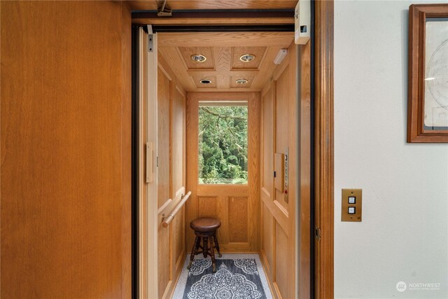 interior space featuring wood ceiling, wood walls, and elevator