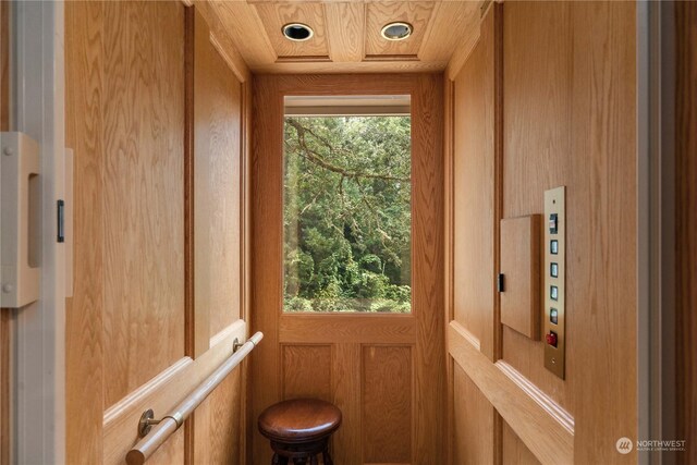 doorway with wood walls, elevator, and wooden ceiling