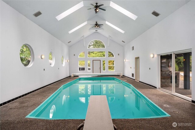 view of swimming pool with ceiling fan, a skylight, a diving board, and a jacuzzi