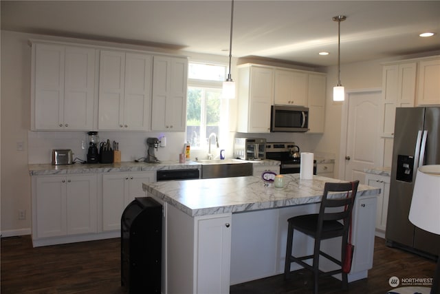 kitchen featuring dark wood-type flooring, a center island, stainless steel appliances, and hanging light fixtures