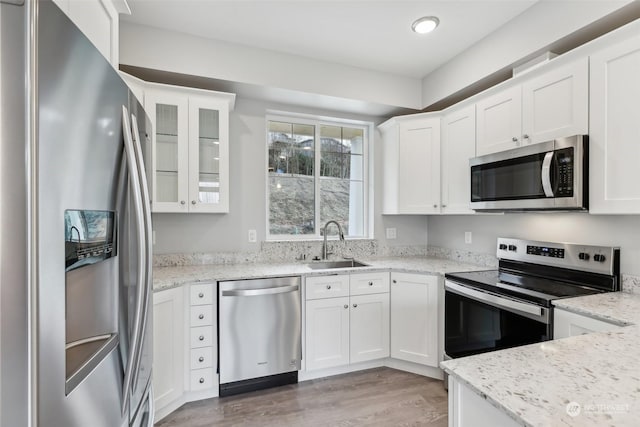 kitchen featuring light stone countertops, stainless steel appliances, and white cabinetry