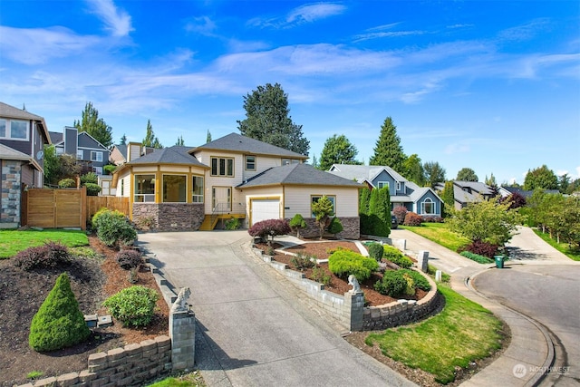 view of front facade with a garage, fence, driveway, stone siding, and a residential view