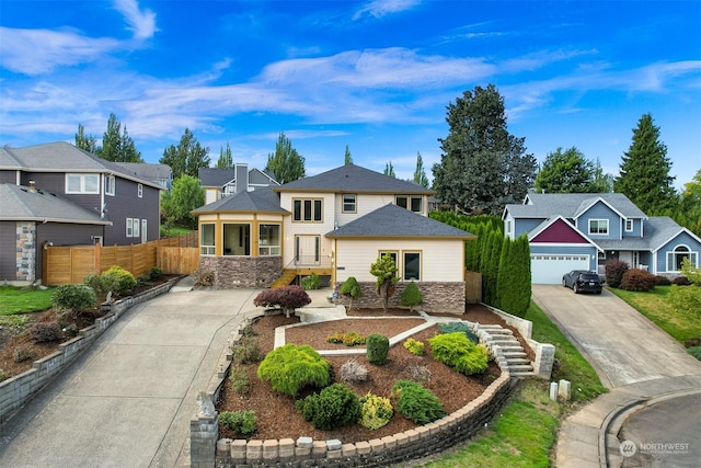 view of front of house featuring stone siding, a residential view, fence, and concrete driveway