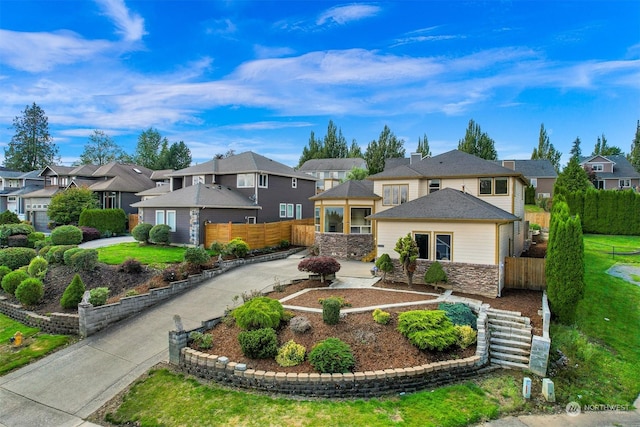 view of front facade with driveway, a residential view, and fence