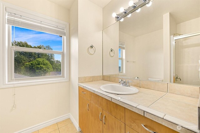 bathroom featuring tile patterned flooring, vanity, toilet, and walk in shower