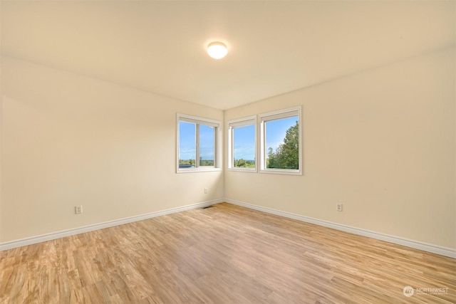 unfurnished room featuring light wood finished floors, visible vents, and baseboards