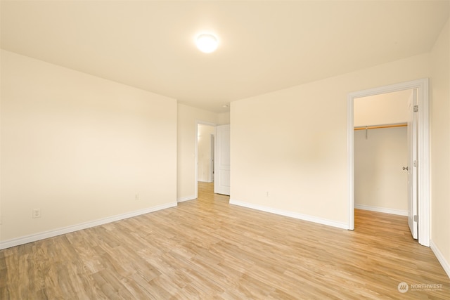 unfurnished bedroom featuring a walk in closet, a closet, and light hardwood / wood-style floors