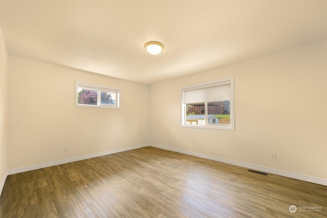 spare room featuring visible vents, baseboards, and wood finished floors