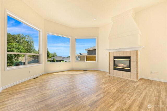 unfurnished living room featuring light wood-type flooring and a tiled fireplace