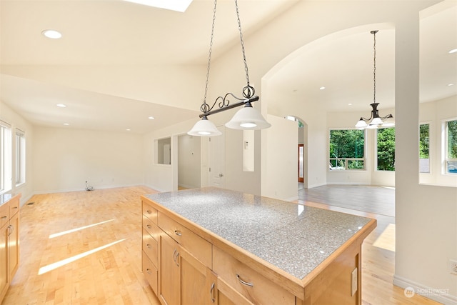 kitchen with light wood-type flooring, pendant lighting, a center island, vaulted ceiling, and light brown cabinets