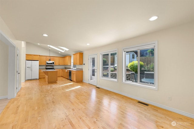 kitchen with white refrigerator with ice dispenser, light wood-style floors, a center island, dishwasher, and stainless steel microwave