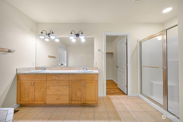 full bathroom with double vanity, a sink, a shower stall, and tile patterned floors