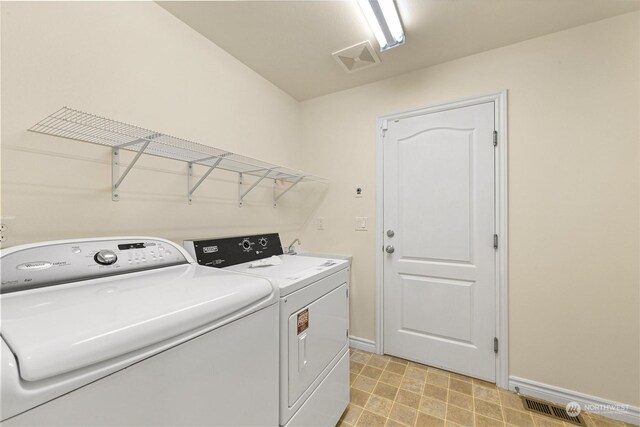 clothes washing area with baseboards, laundry area, visible vents, and washer and dryer