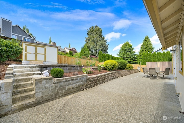 view of patio featuring outdoor dining space, a fenced backyard, and an outbuilding