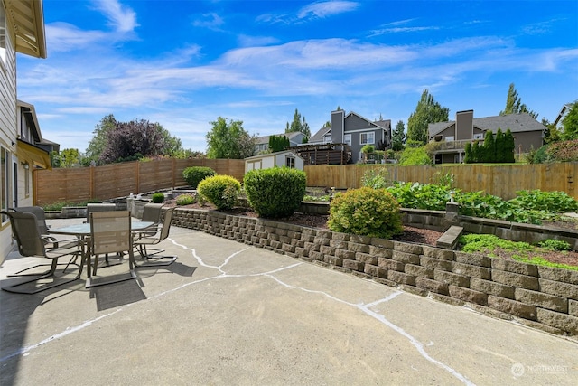 view of patio / terrace featuring a fenced backyard, a shed, outdoor dining area, and an outdoor structure