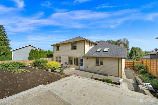 rear view of house with a patio, a chimney, a fenced backyard, and roof with shingles