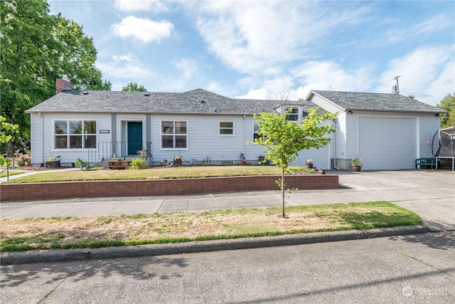 ranch-style house featuring a trampoline, a front yard, driveway, and an attached garage