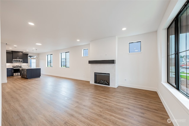 unfurnished living room featuring a wealth of natural light, sink, and light hardwood / wood-style flooring