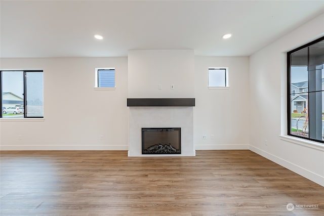 unfurnished living room featuring a tile fireplace and light hardwood / wood-style flooring