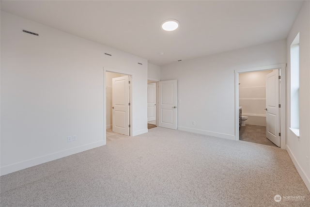 unfurnished bedroom featuring connected bathroom and light colored carpet