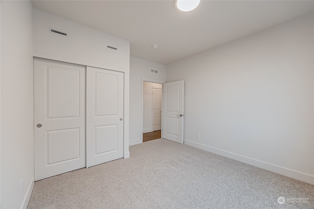 unfurnished bedroom with light colored carpet and a closet