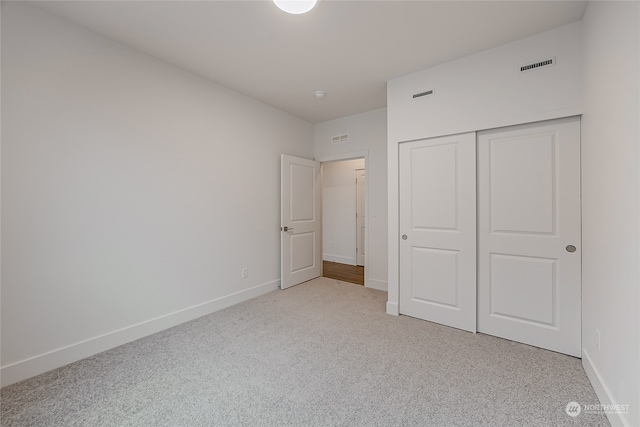 unfurnished bedroom featuring light colored carpet and a closet