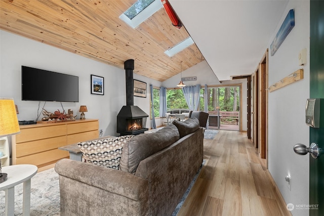 living area with a wood stove, lofted ceiling with skylight, light wood-type flooring, and wood ceiling