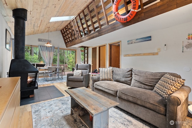 living room featuring a skylight, wooden ceiling, light wood-style flooring, a wood stove, and high vaulted ceiling