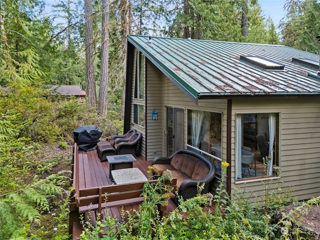 exterior space with metal roof, a standing seam roof, a wooden deck, and an outdoor living space