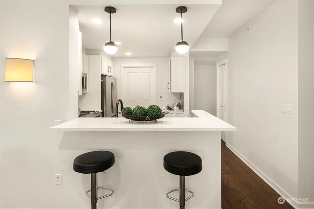 kitchen with appliances with stainless steel finishes, a breakfast bar, kitchen peninsula, and hanging light fixtures