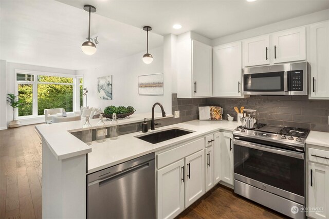 kitchen with white cabinets, stainless steel appliances, dark hardwood / wood-style flooring, sink, and pendant lighting