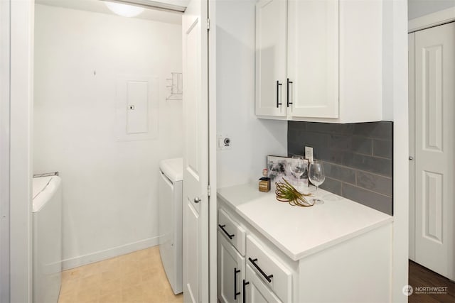 washroom with electric panel, cabinets, and washer and clothes dryer