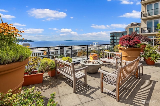 balcony with a water view and an outdoor fire pit