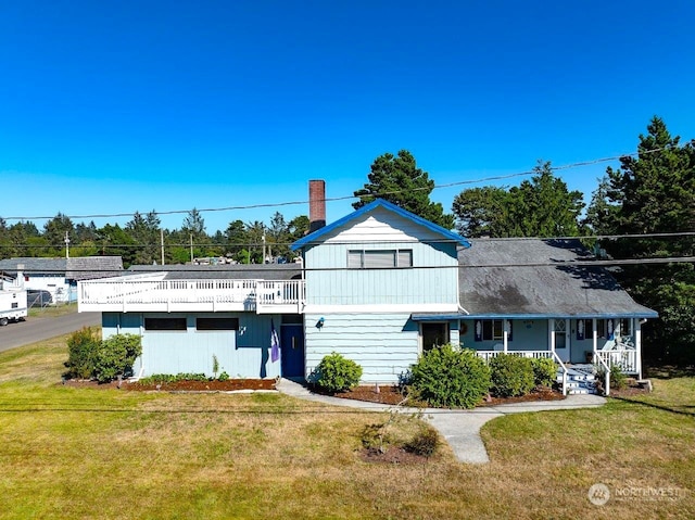 view of front of house featuring covered porch, a chimney, and a front yard