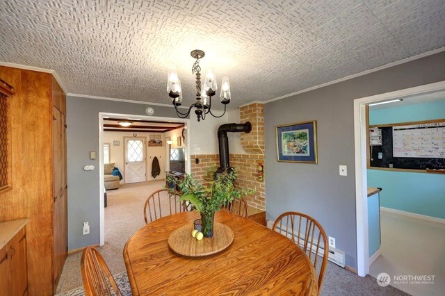 dining room with a wood stove, carpet, a notable chandelier, and ornamental molding